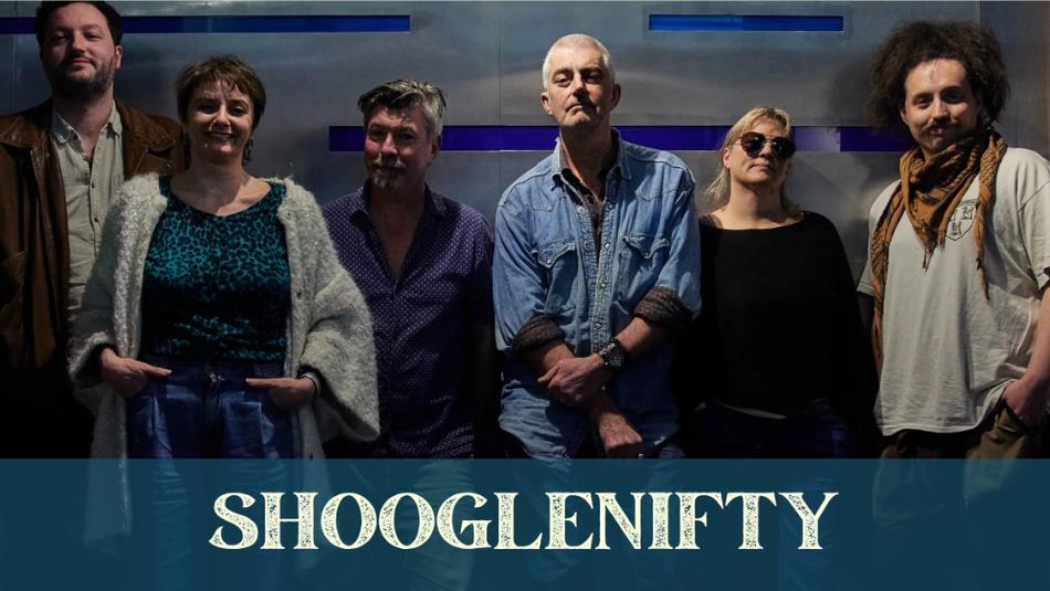 Six people standing against a wall wearing blue tones, with the text 'Shooglenifty' at the bottom