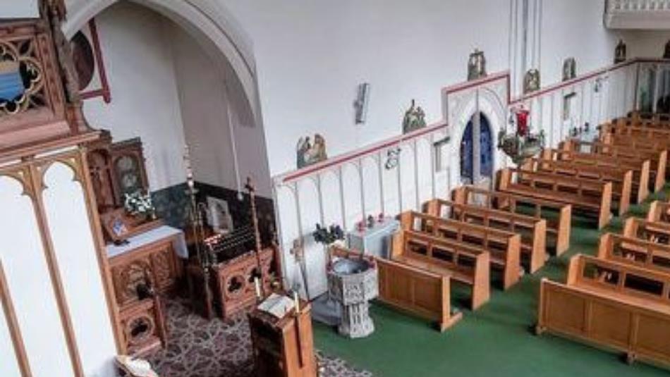 Birds eye view of an ornate church with an altar and pews.