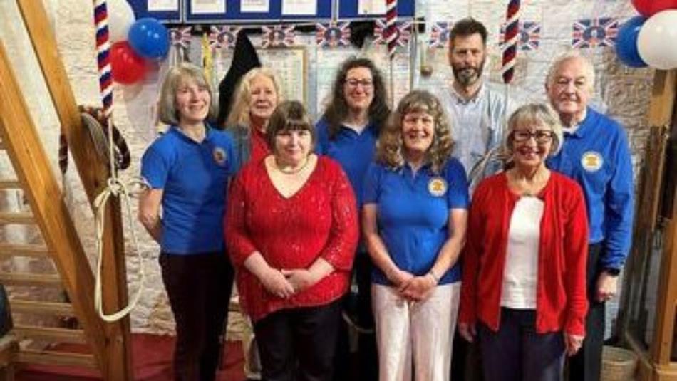A group of eight people wearing red and blue in the ringing chamber of a church.
