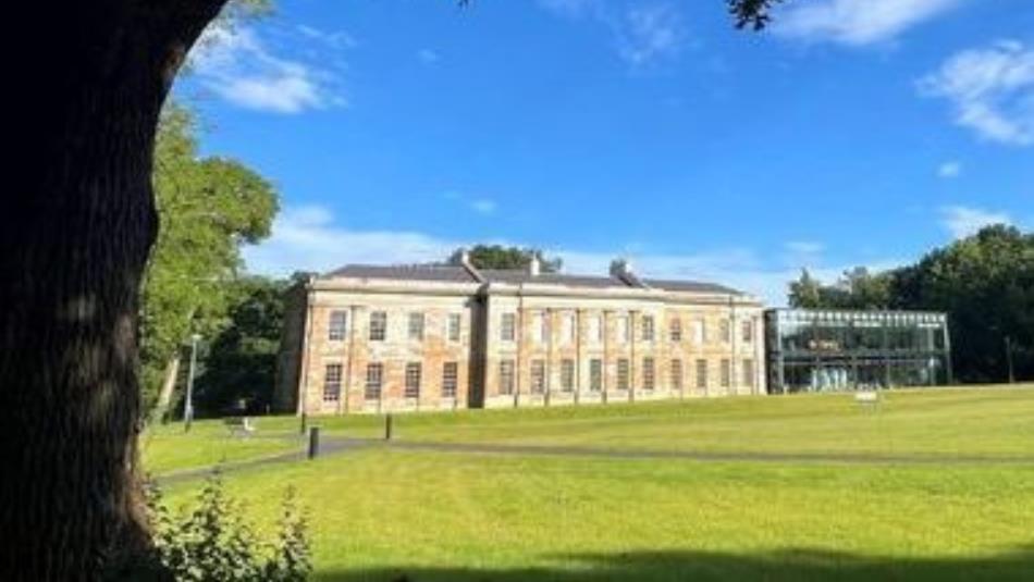 Historical stone building with a grass lawn in front.