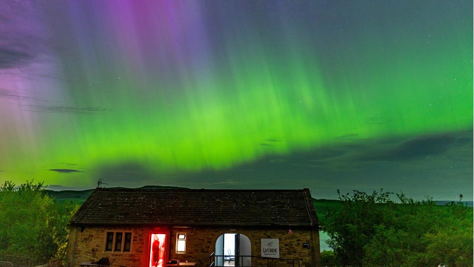 Brightly coloured aurora visible in the dark night sky above Grassholme Observatory and Reservoir