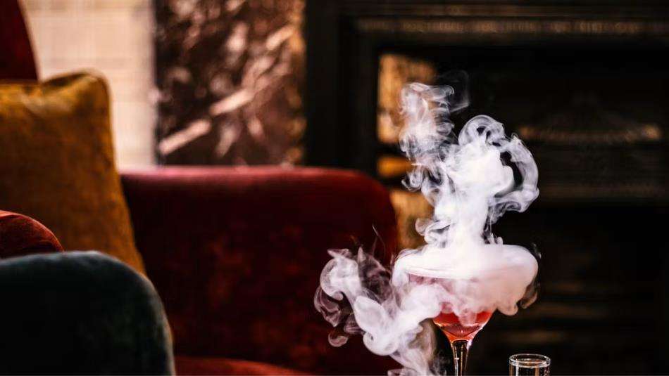 A red cocktail with mist coming off it.