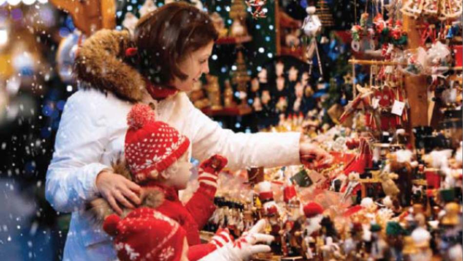 An adult and child browsing through a Christmas market.