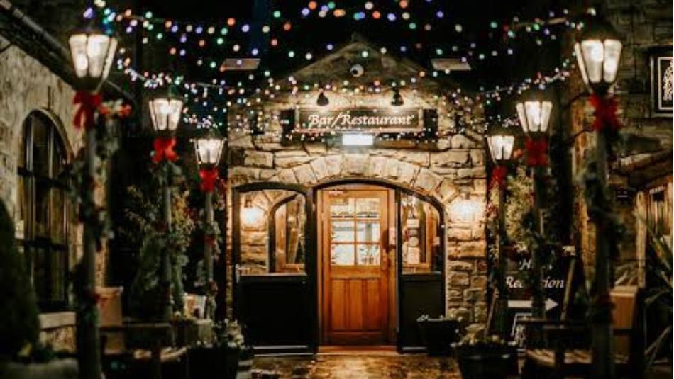 Festive scene of street lamps and Christmas lights decorating a stone building.