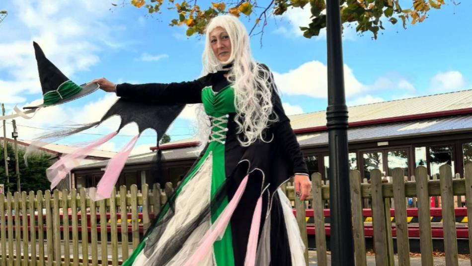 A person dressed as a witch in a green dress and hat at Adventure Valley.