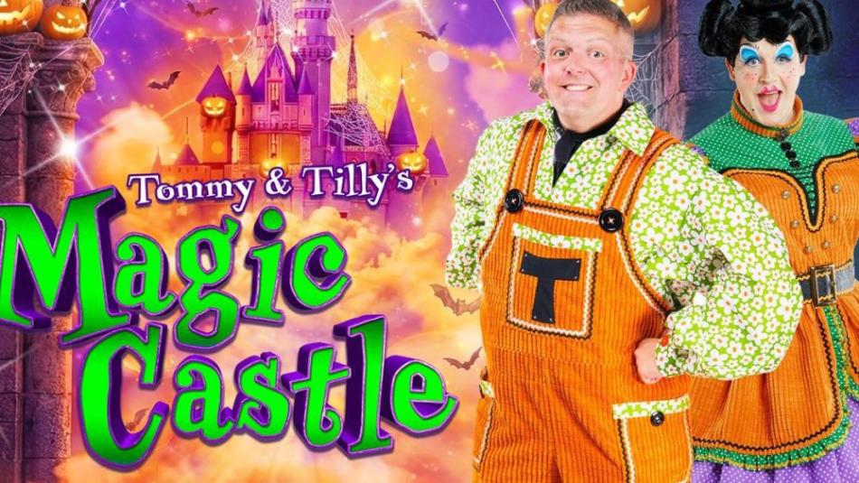 Two people smiling dressed in Halloween themed pumpkin outfits in front of a bright Halloween castle