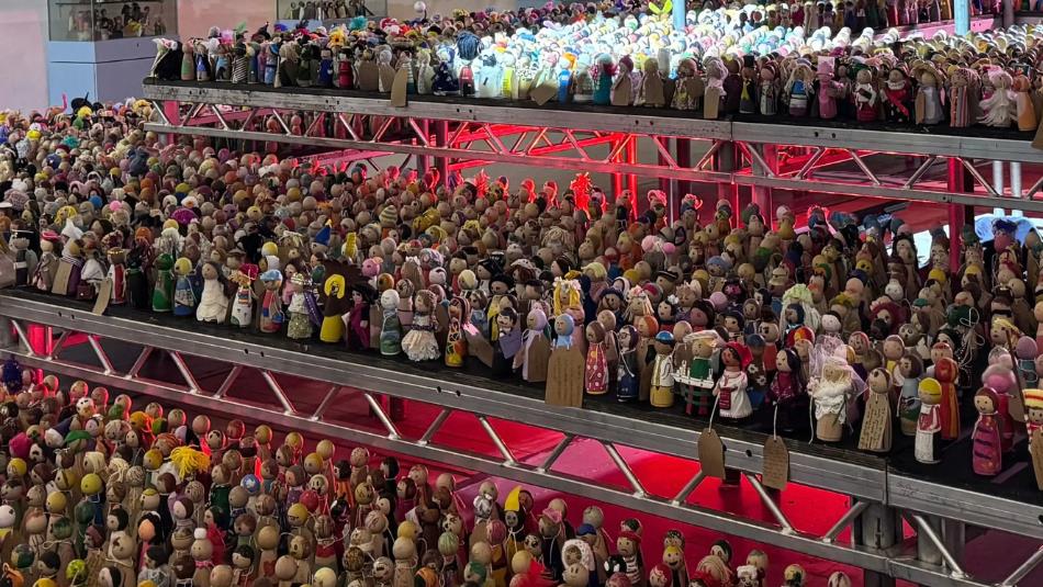An exhibition of many little decorated peg dolls on a stage.