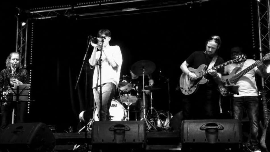 Jazz performers on stage playing their respective instruments, the image is in black and white.