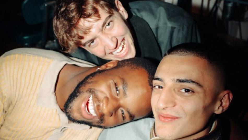 Three people leaning in and smiling at the camera.