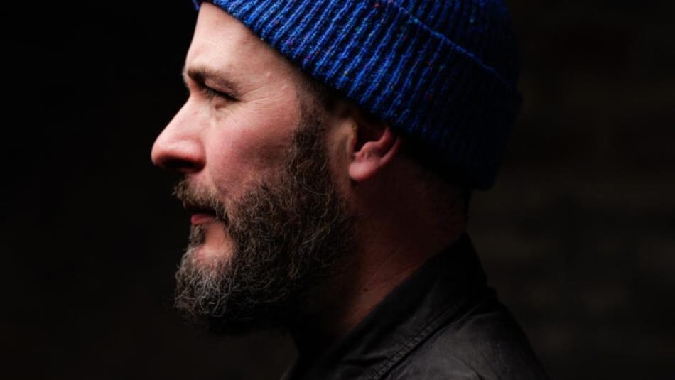 Side profile of a person wearing a blue hat surrounded by darkness.