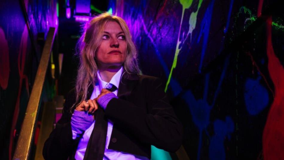 A person looking off to the side wearing a suit on a dark staircase.
