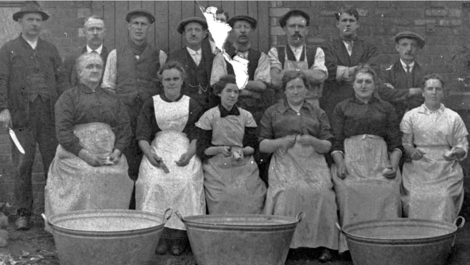 A historic image of a group of people in front of metal tubs.