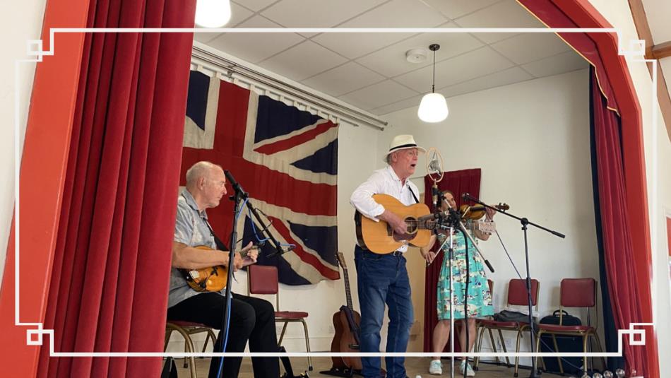 Three people playing folk instruments on a stage.