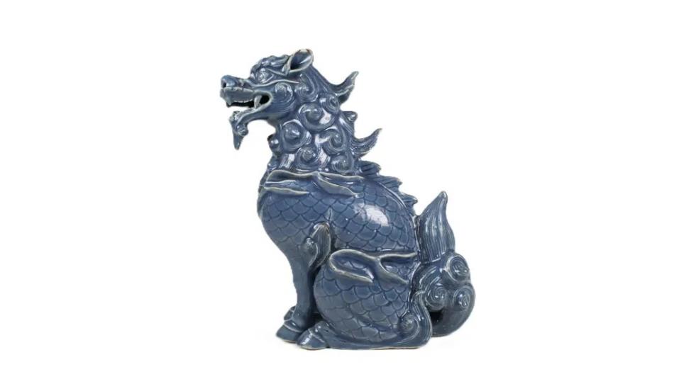 A ceramic animal in the shape of a grey dragon.