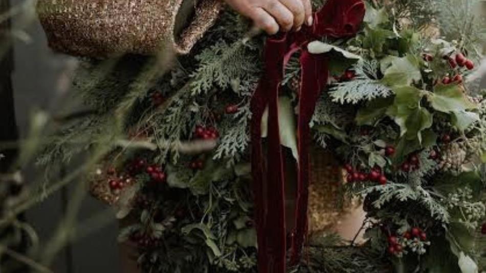A person tending to a festive wreath.