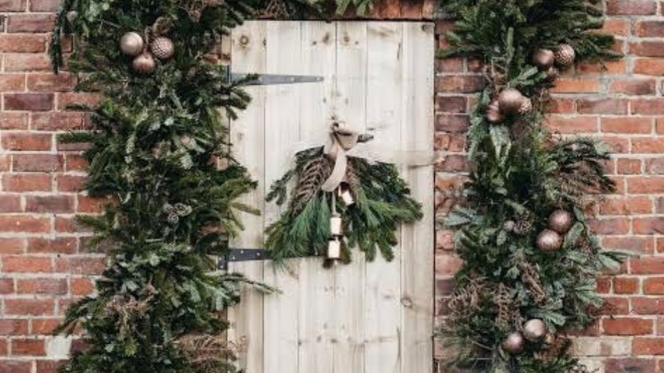 A white wooden door surrounded by festive pine decorations and wreaths.