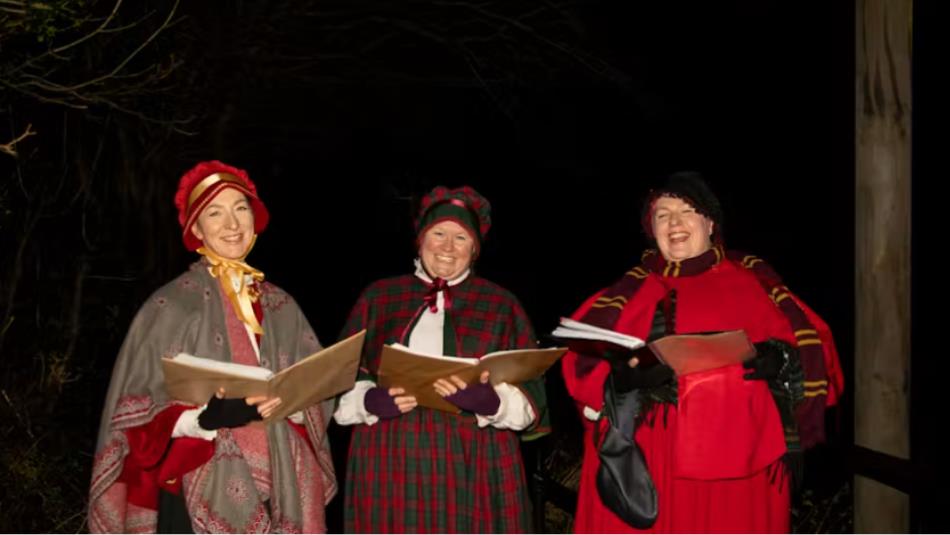 Three smiling vintage carol singers.