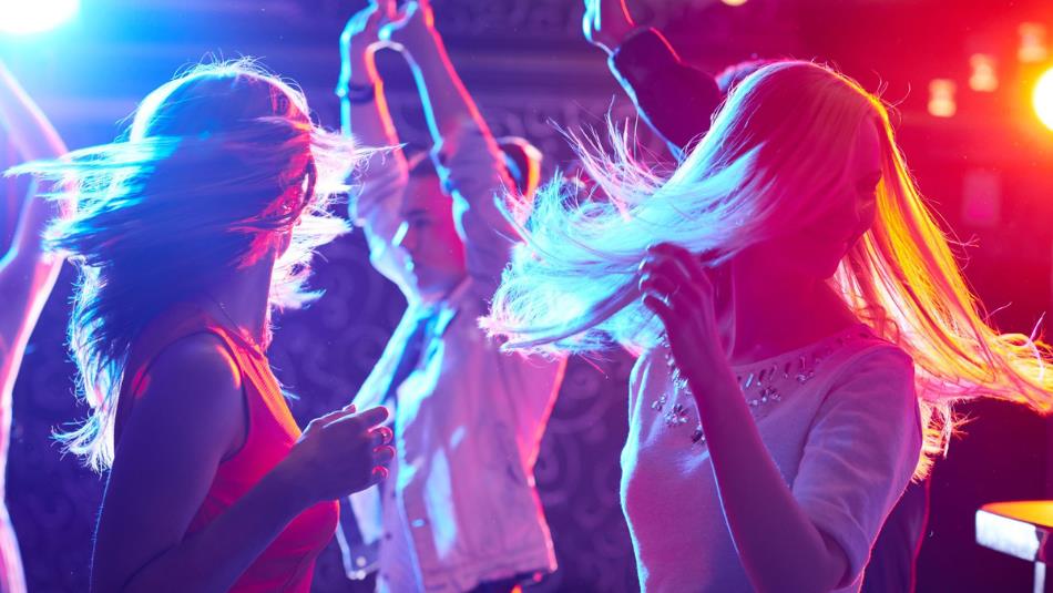 People dancing under colourful lights.