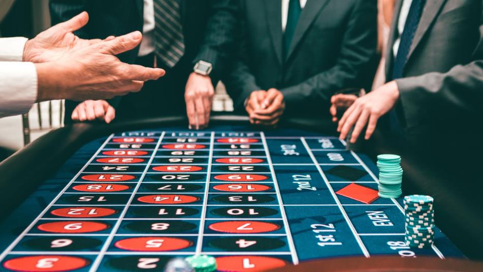 A casino table with people wearing suits gathered around.