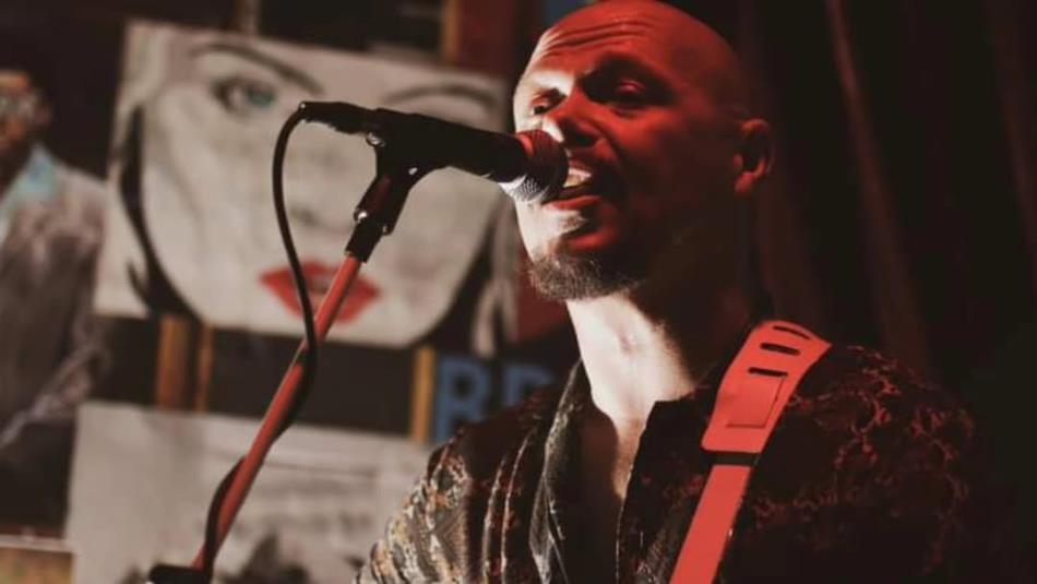 A person singing into a microphone with atmospheric lighting.