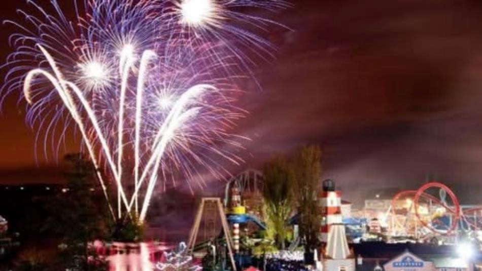 A firework display in the dark sky above a fairground.