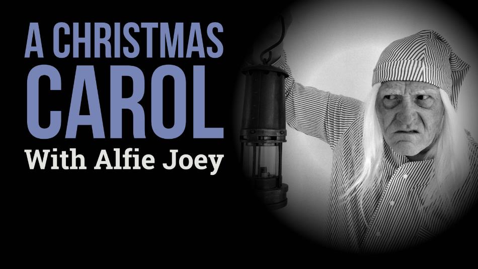 A grumpy Scrooge character, wearing striped pyjamas and a night cap holding a lamp. BLue text which reads 'A Christmas Carol With Alfie Joey' on a bla