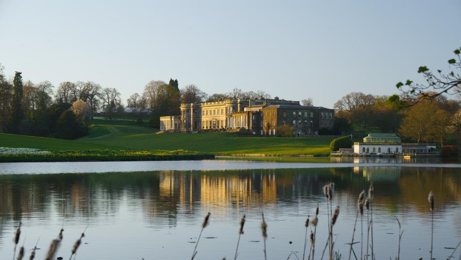 A landscape view of a Wynyard Hall, over a clear lake.