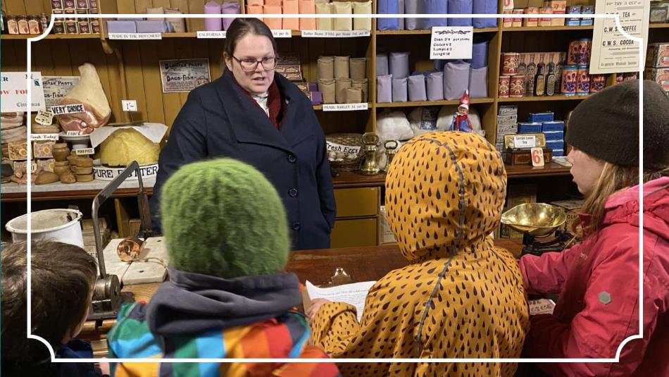 Children standing in an old fashioned shop, talking to the person at the till.