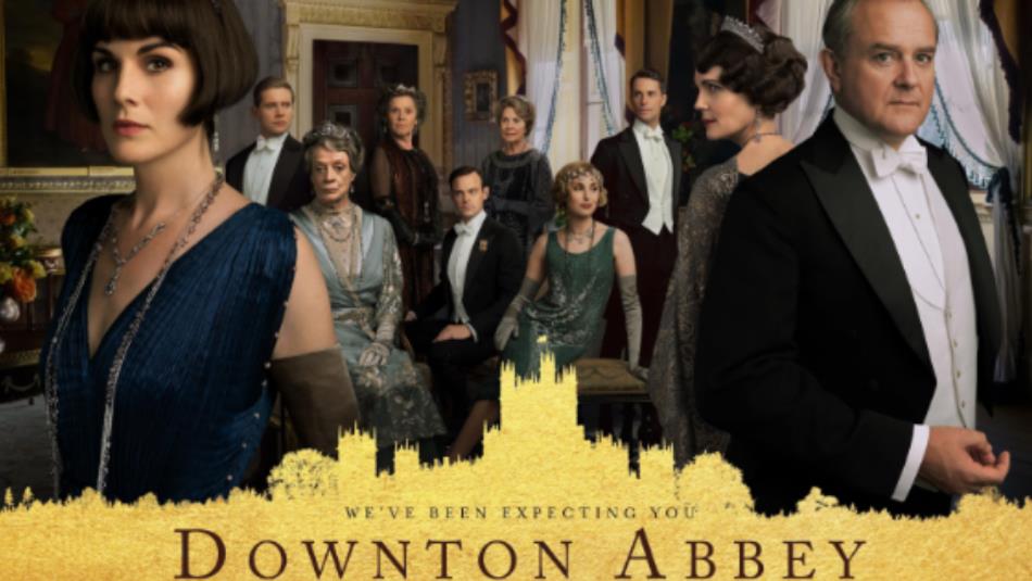 A group of people wearing elegant 1920s outfits in a stately home. The text in a gold silhouette of a manor reads: 'Downton Abbey.'
