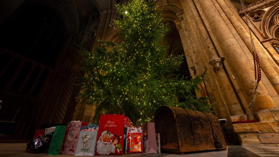 A Christmas tree standing in Durham Cathedral with presents underneath.