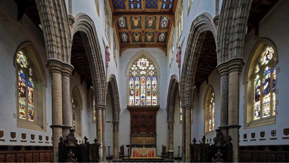 Inside St Peter's Chapel, with ornate stained glass windows and pillars.