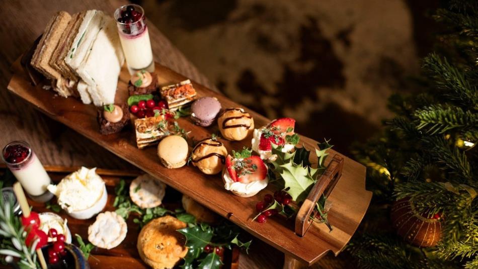 A festive afternoon tea spread decorated with holly leaves and pine trees.