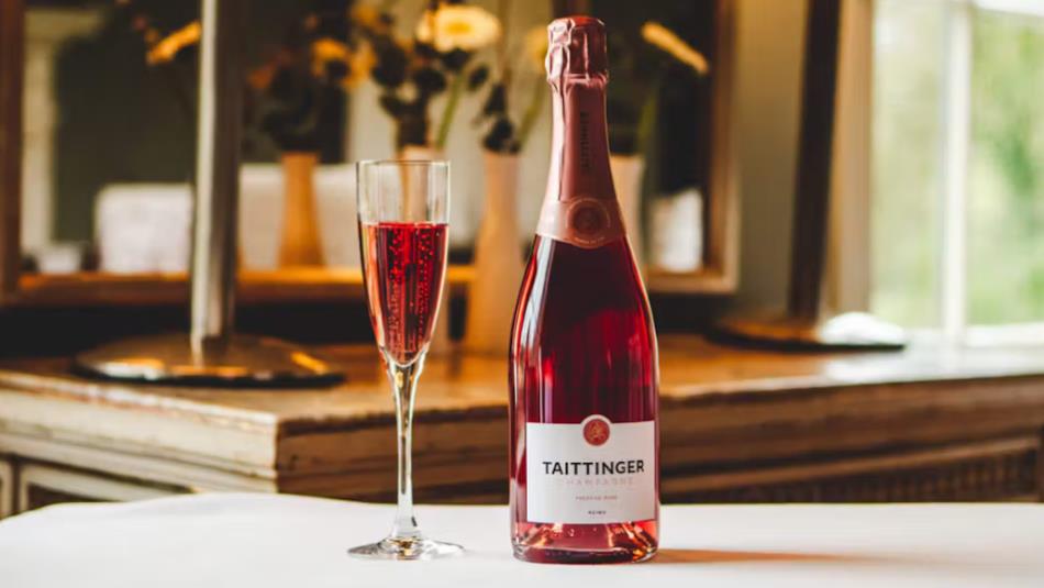 A bottle and half full champagne glass of Tattinger Champagne, a reddish colour, on a white table in Seaham Hall.