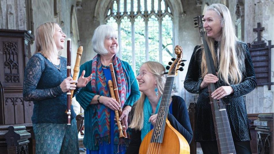 A 4-piece band laughing with each other, holding historical instruments in a church.