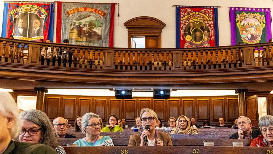 People sat in the hall of Redhills during the conference, Trade Union Banner decorate the walls