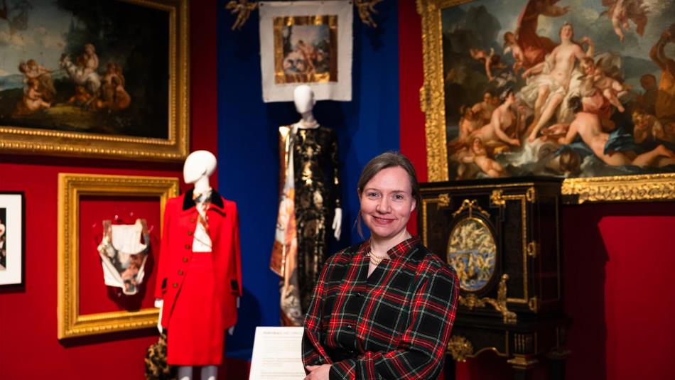 Rachel Whitworth stood in front of mannequins wearing Vivienne Westwood clothing in the Bowes Museum