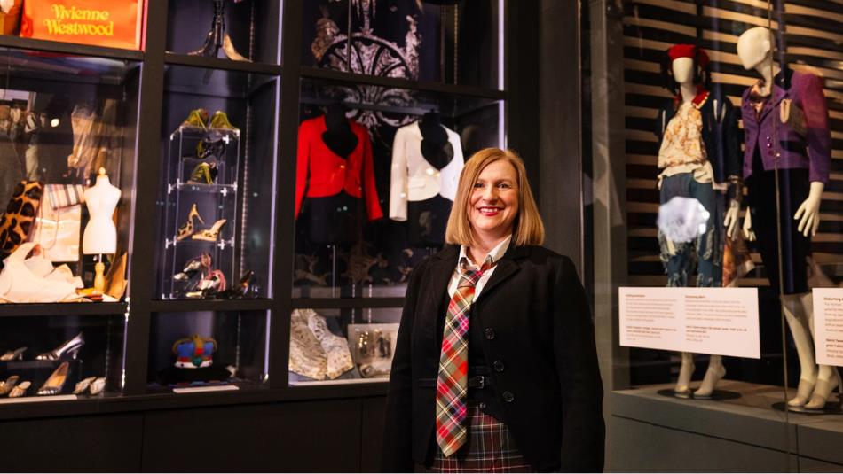 Professor Emma Jane Goldsmith stood infront of the Vivienne Westwood exhibit at The Bowes Museum, wearing a large tartan tie.