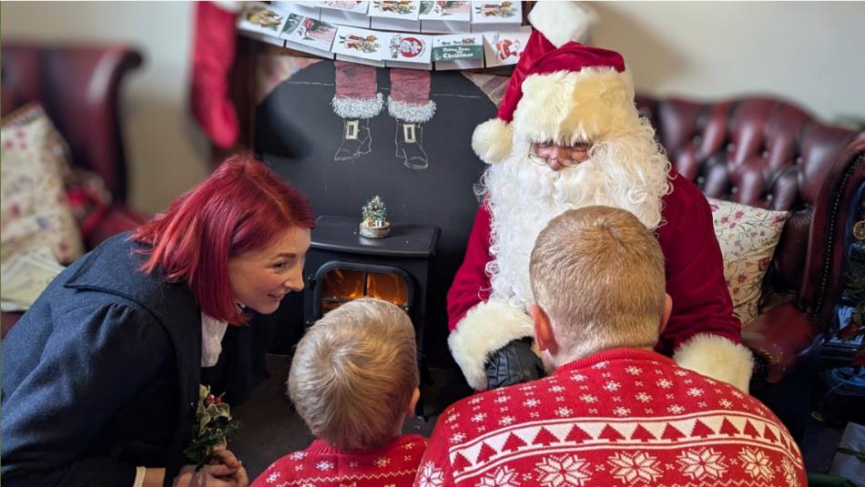 Father Christmas sitting in an armchair greeting a young family in the cafe