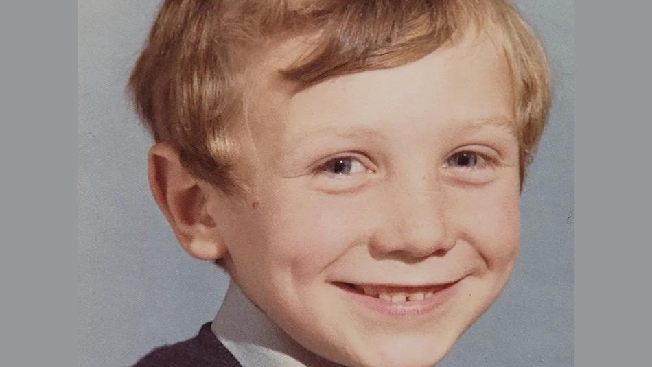 School photo of a small child, smiling against a grey background