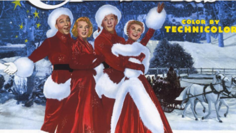 Four people wearing red festive clothing, hugging and laughing in the snow with a horse drawn carriage behind.