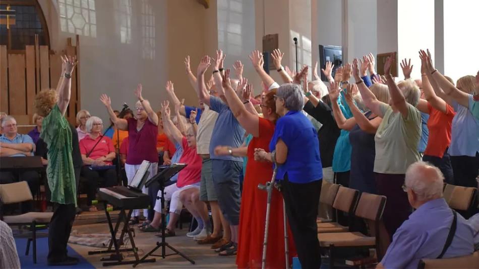 People singing with their hands in the air in a church-like building