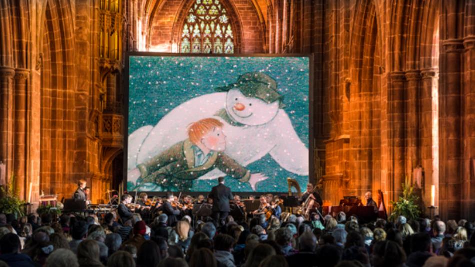 The Snowman playing on a large projector in Durham Cathedral, with a large crowd watching