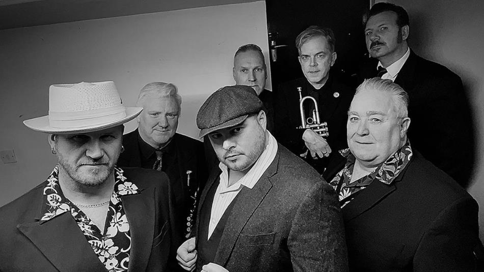 The Revolutionaires & Tyne Valley Big Band stood in a group looking at the camera. The image is in black and white.