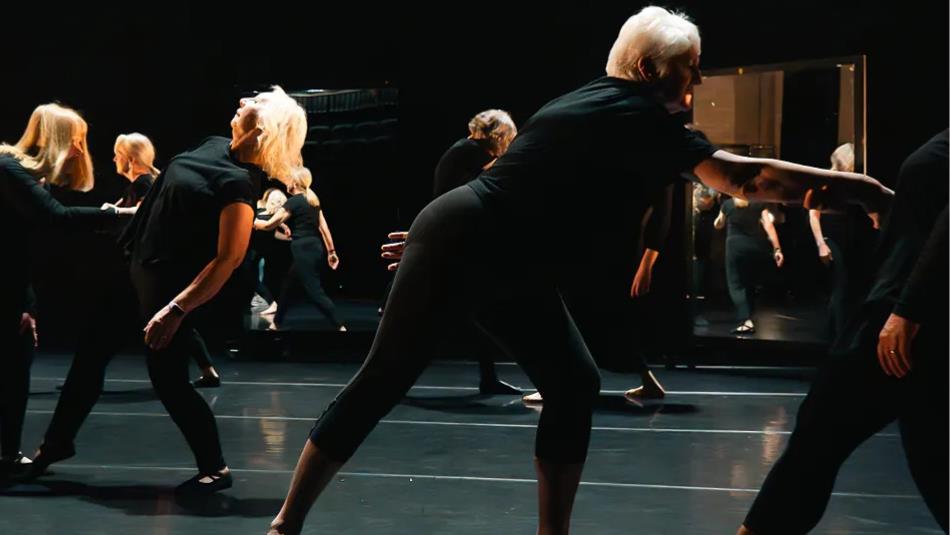 People dancing on a dark stage with low lit lighting.