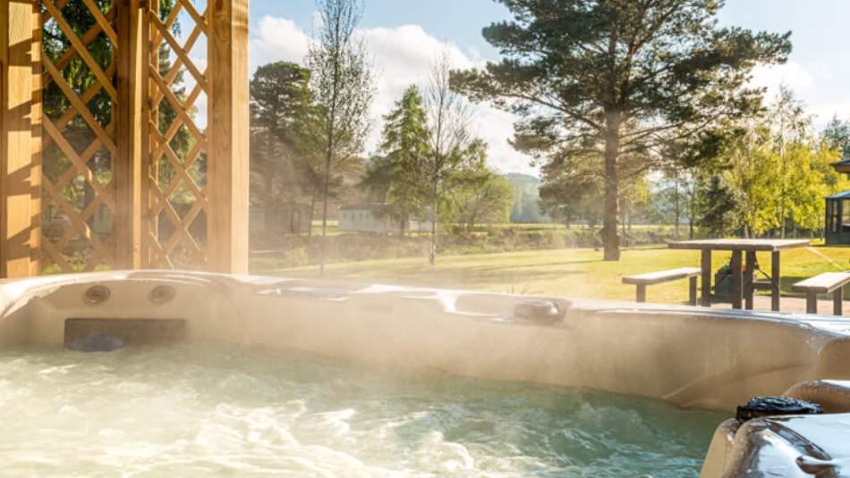 View from a steaming hot tub with trees and a picnic table in the distance.