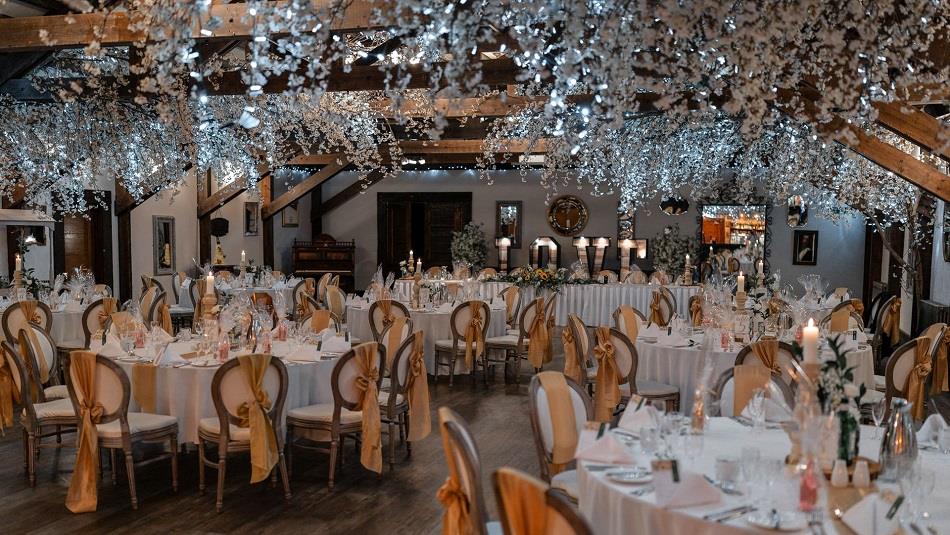 Tables and chairs dressed beautifully in white, with flowers and fairy lights,  for a wedding at South Causey Inn