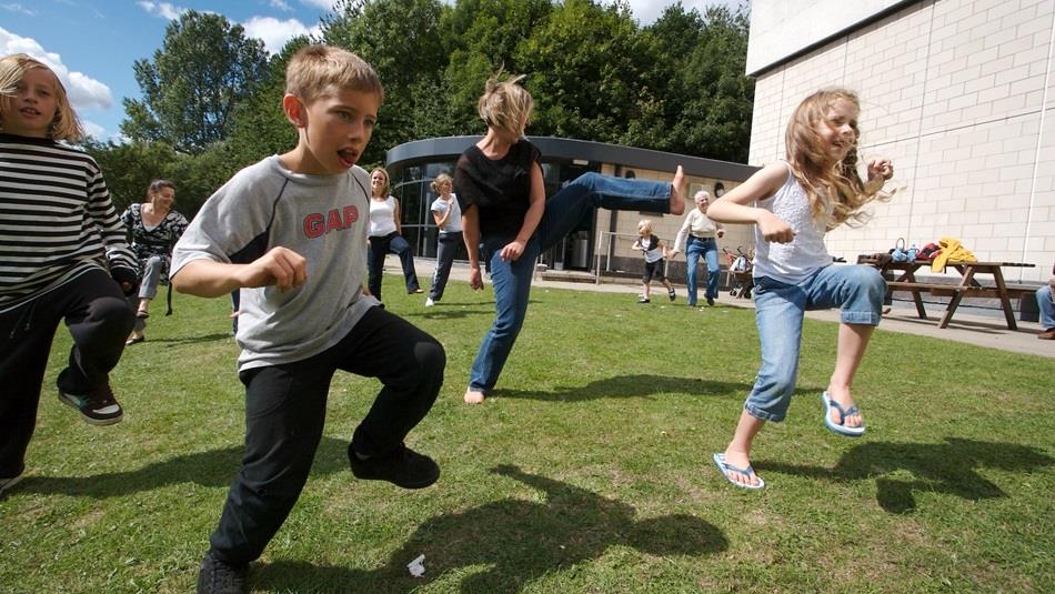 Adults and children taking part in an outdoor activity at IncludFEST