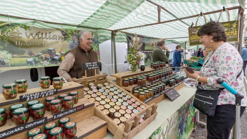 Chutney trader. Woman looking at stall and holding purse.