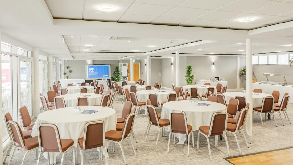 Room set out for a conference with round tables and chairs