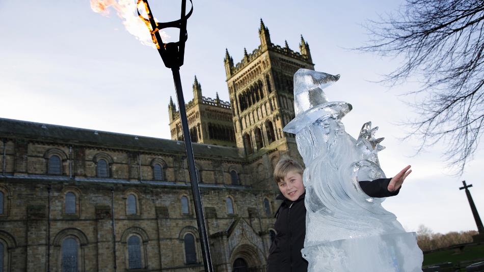 child poses with ice culture and flame lit torch outside Durham Cathedral.